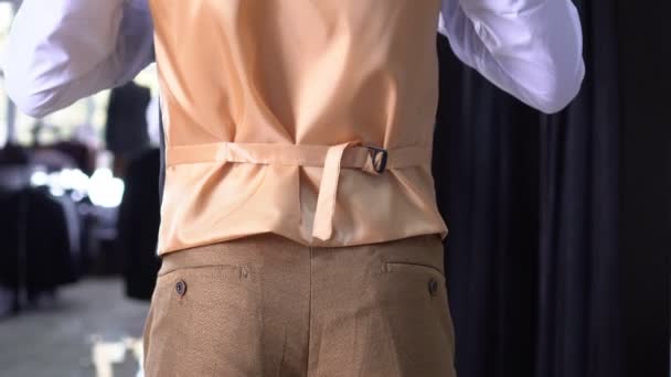 Ein Mann in einem Bekleidungsgeschäft probiert einen klassischen Anzug vor dem Spiegel an — Stockvideo