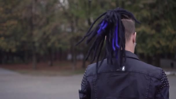An informal punk man with hair and dreadlocks listening to music outdoors — Stock Video
