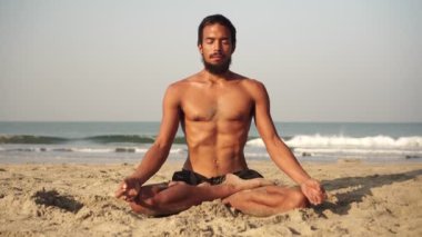 Genç bir adam lotus pozisyonunda yoga ve meditasyon yapıyor.