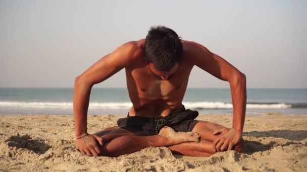 Ein junger Mann praktiziert Yoga im Freien vor dem Hintergrund des Meeres — Stockvideo