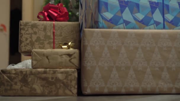 Navidad, una mujer atractiva mira detrás de las cajas con regalos. Celebración de Año Nuevo — Vídeo de stock