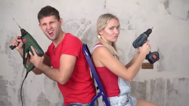 Positief jong getrouwd stel met gereedschap op de achtergrond van woningrenovatie — Stockvideo