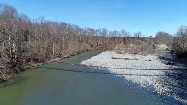 Hängebrücke über einen Gebirgsfluss, Vorfrühling — Stockvideo