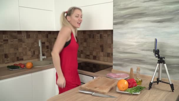Ung sexet kvinde blogger danser i køkkenet og filmer sig selv på smartphone kameraet – Stock-video