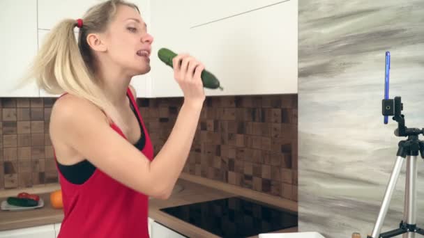 Jonge aantrekkelijke vrouw blogger zingen en dansen in de keuken voor een smartphone — Stockvideo
