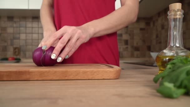 Une femme dans la cuisine coupe un oignon rouge avec un couteau, au ralenti — Video