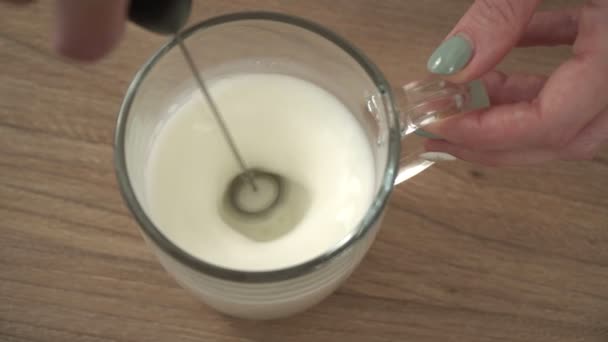 Beat the milk in a mug using a frother. Hand mixer for milk. Making foamy milk with frother — Stock Video