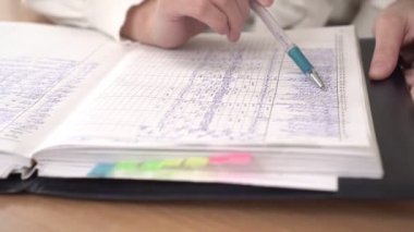 Okul günlüğü ya da notları olan kayıt, yakın çekim. Öğretmen okul günlüğünü kontrol ediyor.