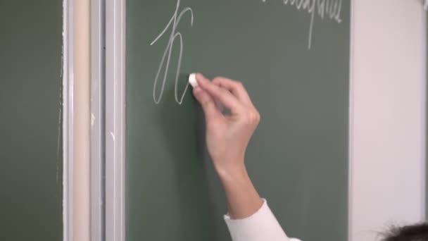 Ryska språklärare skriver med krita på en svarta tavlan i skolan — Stockvideo