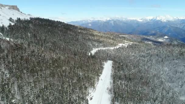 Bosque de invierno y montañas, carretera o carretera, vista aérea. Concepto de viaje de invierno — Vídeos de Stock