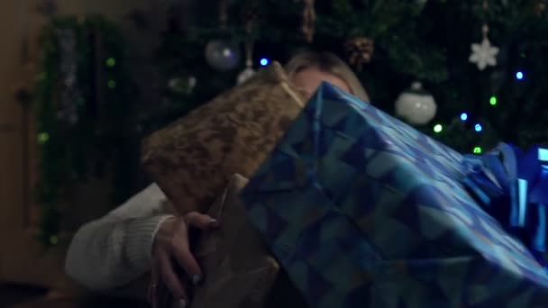 Жінка кидає коробки з подарунками на фоні новорічної або різдвяної ялинки — стокове відео