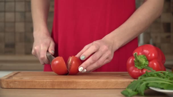 Kvinna skär tomater i köket på en skärbräda, närbild — Stockvideo