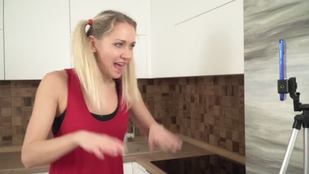 Young woman blogger prepares in the kitchen and shoots video on a smartphone — Stock Video