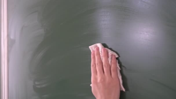 Una persona, profesor o estudiante borra la tiza de una pizarra en una clase escolar — Vídeos de Stock