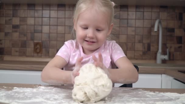 Dítě hnětá těsto na kuchyňském stole. 4-5 letá dívka se učí vařit — Stock video