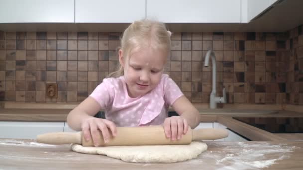 부엌에 있는 한 어린이가 압연 핀 으로 반죽을 굴려 낸다. 어린 소녀가 요리를 배우고 있다 — 비디오
