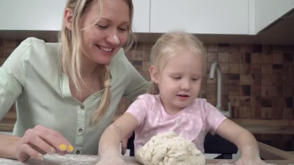 Mamá e hija cocinan juntas en casa en la cocina y amasan la masa — Vídeos de Stock