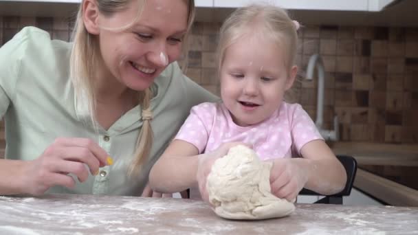 Ευτυχισμένη οικογένεια, η μαμά και η κόρη ετοιμάζουν γλυκά από το ζυμάρι στην κουζίνα. Μια γυναίκα μαθαίνει στο παιδί να μαγειρεύει. — Αρχείο Βίντεο