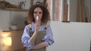 Atölyedeki genç çekici kadın sanatçı. Ressamın portresi beyaz bir tuvalde.