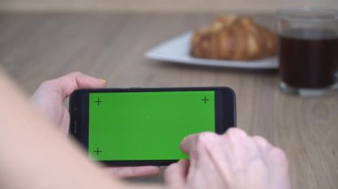 Yeşil ekranlı akıllı telefon. Bir adam yeşil ekran ile telefona tıklıyor, yakın plan.
