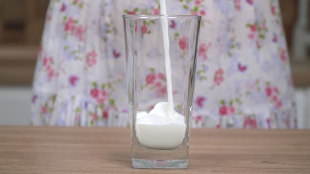 Жінка на кухні вливає молоко в склянку, повільний рух. Склянка свіжого сільського молока крупним планом — стокове відео