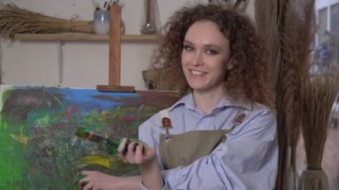 Parlak bir soyut resmin arka planında mutlu modern sanatçı kadın.