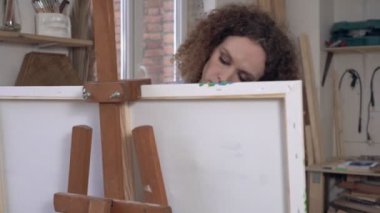 Modern sanatçı yenilikçi bir resim çiziyor ve elleriyle tuval üzerinde bir sanat eseri yaratıyor.