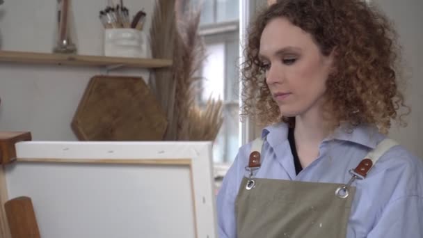 Belle jeune femme artiste peint un tableau sur toile dans le studio — Video