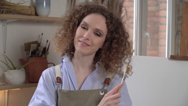 Linda jovem artista no fundo de uma tela branca ou pintura — Vídeo de Stock