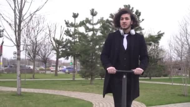 Fiatal, modern férfi üzletember, elektromos robogóval jár. Környezetbarát városi közlekedési koncepció — Stock videók