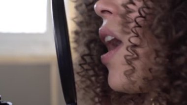 Kadın mikrofona şarkı söylüyor, yakın plan. Güzel bir kadın şarkıcı bir kayıt stüdyosunda şarkı söylüyor..