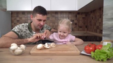 Baba ve çocuk mutfakta yemek pişiriyorlar. Babası kızına yemek yapmayı öğretiyor.