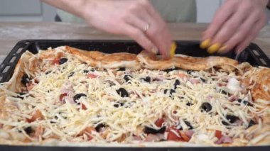 Mutfakta bir kadın peynirli ve sebzeli ev yapımı pizza hazırlıyor.