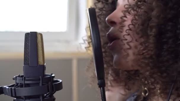 Женщина поет в микрофон в студии звукозаписи, лицо крупным планом — стоковое видео