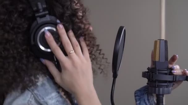 Певица в студии звукозаписи. Молодая женщина поет в микрофон — стоковое видео