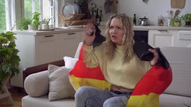 Μια γυναίκα φίλαθλος ή ποδοσφαιριστής με τη σημαία της Γερμανίας παρακολουθεί τηλεόραση στο σπίτι. Γερμανός φίλαθλος — Αρχείο Βίντεο