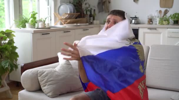 Tifoso russo di sport o calcio a casa sul divano con la bandiera della Russia. Un fan russo guarda la TV a casa — Video Stock