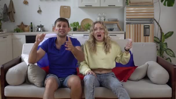 Famille couple de fans de football à la maison avec le drapeau de la Russie. Les fans de sport russes regardent la télévision diffusée à la maison sur le canapé — Video