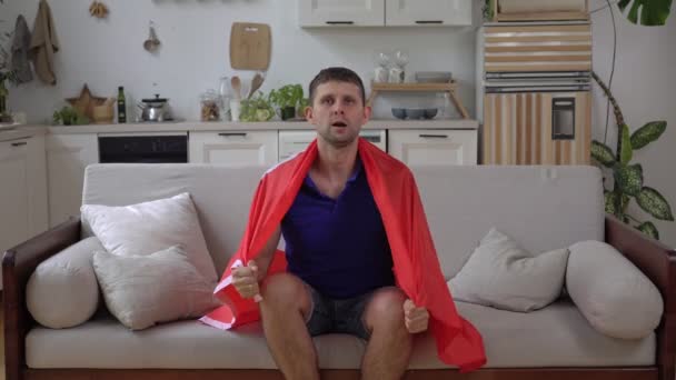 Appassionato di sport maschile a casa con la bandiera della Turchia. tifoso di calcio turco guarda la TV e si rallegra per la vittoria — Video Stock