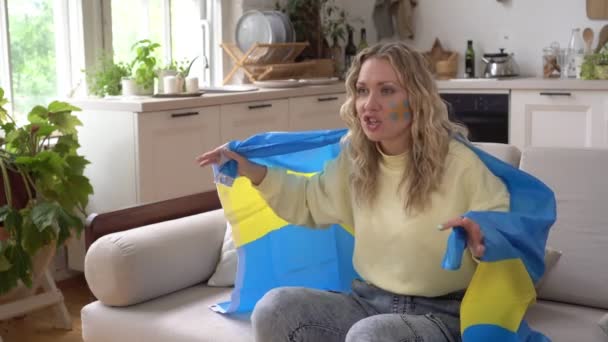 Mujer fanática de los deportes en casa con la bandera de Suecia. Un fanático del fútbol sueco ve la televisión y se alegra por la victoria — Vídeos de Stock