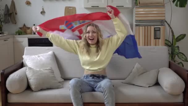 Amante dello sport femminile a casa con la bandiera della Croazia. Un tifoso croato di calcio guarda la TV e gioisce per la vittoria — Video Stock