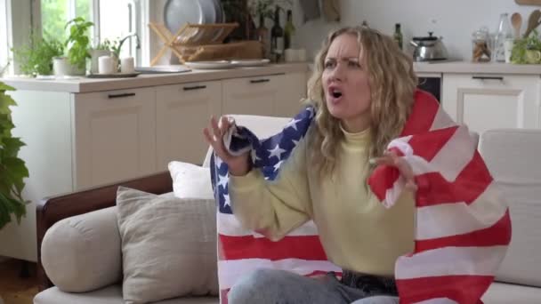 Abanico deportivo en casa con la bandera de USA. Mujer fan del fútbol americano mira la televisión y se regocija por la victoria, cámara lenta — Vídeos de Stock