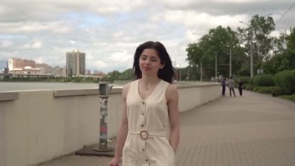 Genç ve çekici bir kadın nehir boyunca şehirde yürüyor. — Stok video