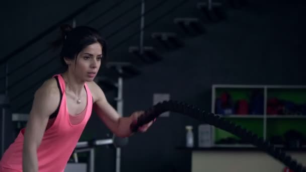 Jeune femme sportive s'entraîne avec des cordes dans la salle de gym. Femme active va dans le sport dans la salle de gym — Video