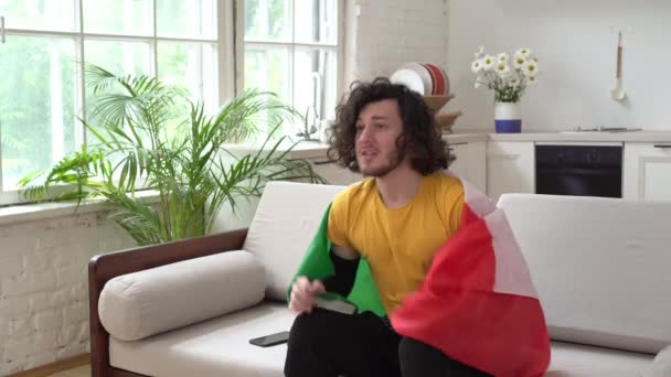 Итальянский футбольный фанат смотрит телевизор дома с флагом Италии — стоковое видео