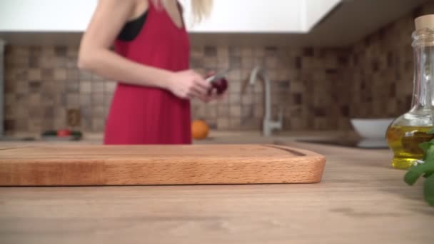 Placă de tăiere din lemn în bucătărie de aproape. O tânără gătește în bucătărie — Videoclip de stoc