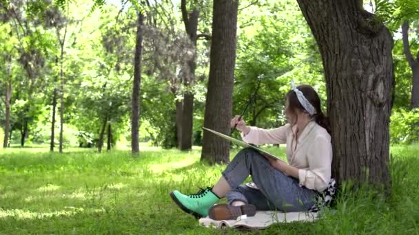 Junge attraktive Künstlerin malt auf die Natur. Frau malt Bild im Park — Stockvideo
