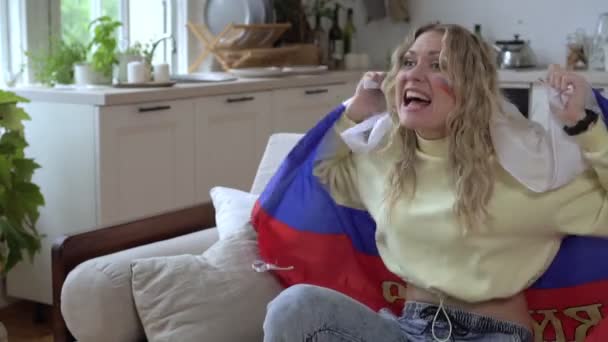Rus milli takımının bir hayranı evde televizyon seyrediyor ve elinde bir bayrak sallıyor, ağır çekim. — Stok video