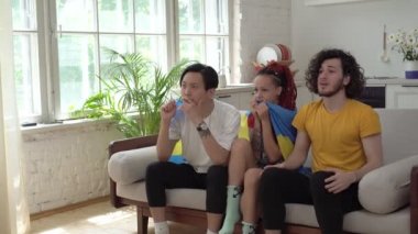 Mutlu İsveçli taraftarlar evde televizyonda spor izliyor. İsveç bayrağı taşıyan futbol taraftarları