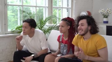 Mutlu arkadaşlar TV 'de maç seyrediyor. Genç taraftarlar evdeki zafere seviniyorlar.